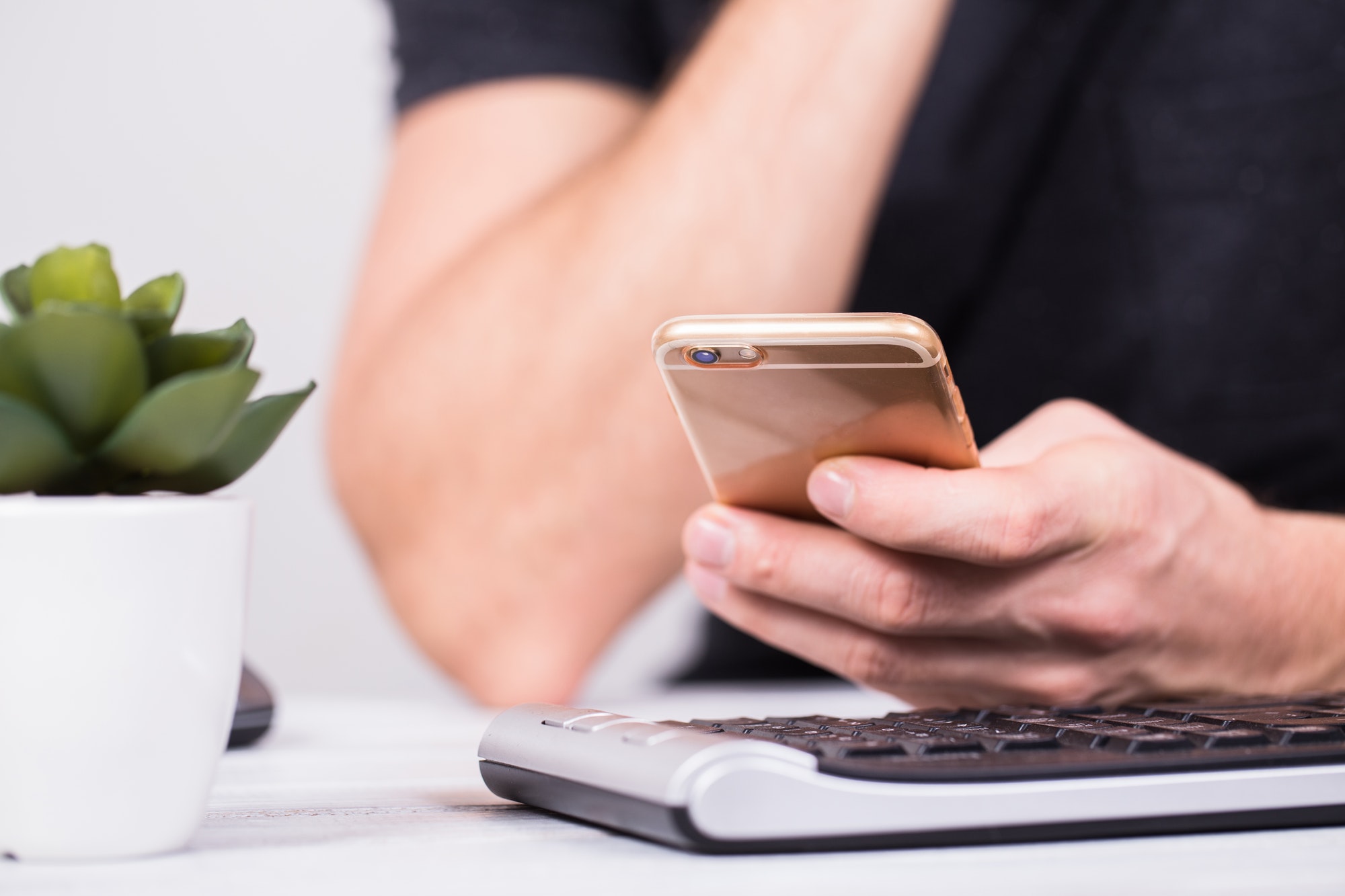 Hands of businessman using a mobile phone and keyboard